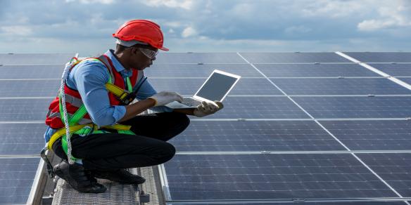 technican on solar roof  with laptop